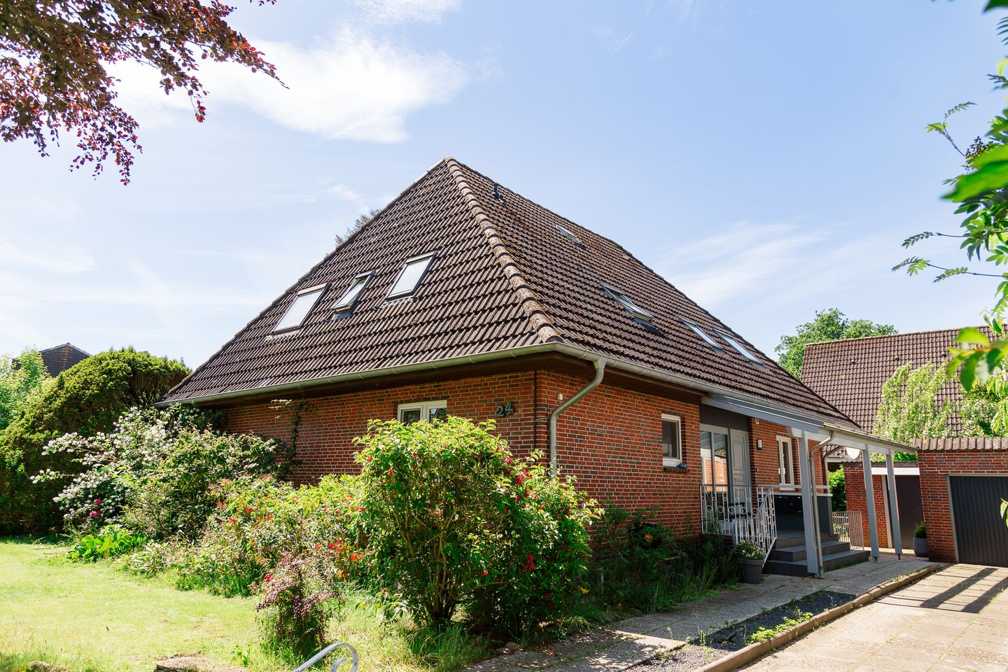 Haus Bilby von außen: Klinkerhaus mit Ziegeldach und blühenden Sträuchern im Vorgarten