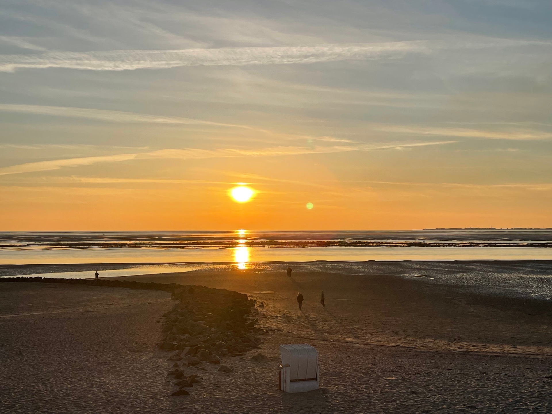 Sonnenuntergang über dem Wattenmeer bei Utersum, vorn ein Strandkorb