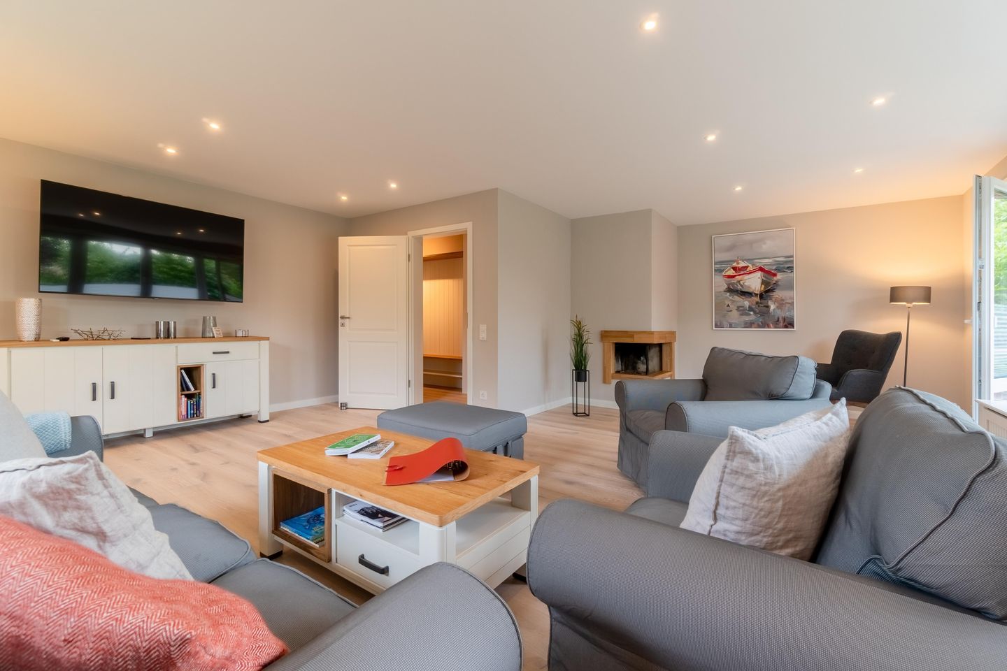 Wohnzimmer mit grauer Sitzgruppe, Couchtisch, Wandfernseher und Kamin
